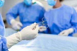 Low Angle Shot in the Operating Room, Assistant Hands out Instruments to Surgeons During Operation. Surgeons Perform Operation. Professional Medical Doctors Performing Surgery. photo