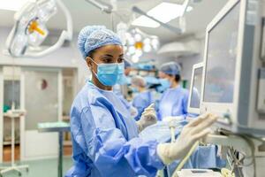 Concentrated Surgical team operating a patient in an operation theater. Well-trained anesthesiologist with years of training with complex machines follows the patient throughout the surgery. photo