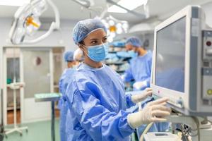 anestesiólogo que realiza un seguimiento de las funciones vitales del cuerpo durante la cirugía cardíaca. cirujano mirando el monitor médico durante la cirugía. monitor de control médico para el estado de salud del paciente. foto