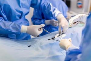 Group of surgeons doing surgery in hospital operating theater. Medical team doing critical operation. Group of surgeons in operating room with surgery equipment. Modern medical background photo