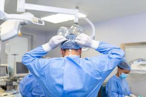 Rear view of male surgeon wearing surgical mask in operation theater at hospital photo