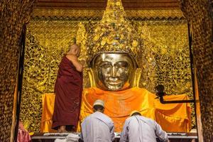 mandala, myanmar - jul 17, 2018-senior monje lavar el cara de Mahamuni Buda imagen a Mahamuni templo. el más muy venerado Buda imagen en el país. foto