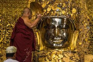 mandala, myanmar - jul 17, 2018-senior monje lavar el cara de Mahamuni Buda imagen a Mahamuni templo. el más muy venerado Buda imagen en el país. foto