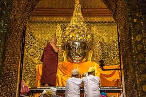 mandala, myanmar - jul 17, 2018-senior monje lavar el cara de Mahamuni Buda imagen a Mahamuni templo. el más muy venerado Buda imagen en el país. foto