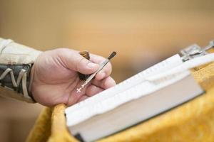 Priest's hand with anointing brush and bible. photo