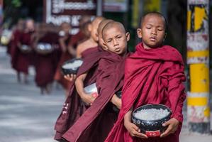 BAGAN, MYANMAR - JUL 18, 2018-Buddhist novices walk to collect alms and offerings along the road at Bagan, Myanmar. photo