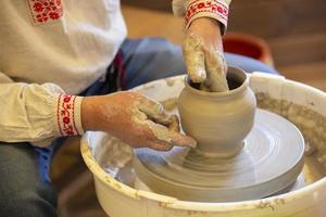 The hands of the master make a pot of clay. photo