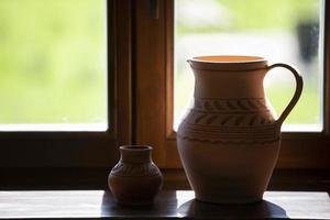 On the windowsill there are rustic clay jugs. photo