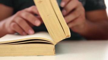 Student browse over book pages at desk, student research from books and looking for information, selective focus video