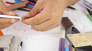 arquitecto estudiante dibujo con regla brújulas en papeleo, arquitecto estudiante trabajando para diseño Plano de el proyecto y real inmuebles edificio, selectivo atención video