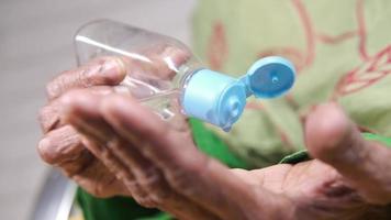 vicino su di anziano donna mano utilizzando disinfettante gel per prevenire virus video