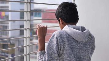 verdrietig tiener- jongen op zoek door venster video