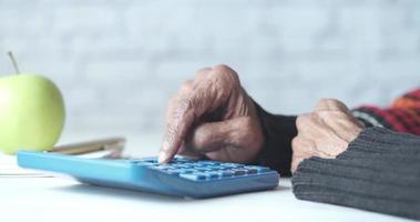 senior vrouw hand- gebruik makend van rekenmachine Aan bureau video