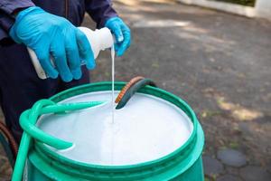 exterminate termite control company employee is using a termite sprayer at customer's house and searching for termite nests to eliminate. exterminate control worker spraying chemical insect repellant photo