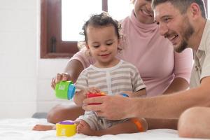 padres con pequeño niña tener divertido jugando con tu nuevo juguetes en el dormitorio juntos. juguetes ese mejorar para niños pensando habilidades. foto