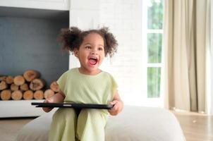 A young bright cute little girl with her trusty tablet that makes her happy and joyful. photo