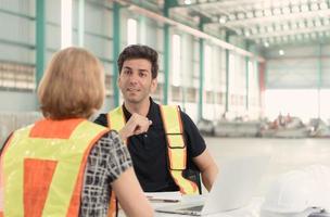 Meeting between designer and warehouse manager to organize the arrangement of product shelves in a huge, empty warehouse. photo