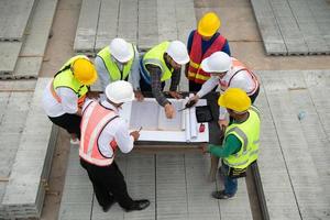 construcción ingenieros, arquitectos, y capataces formar un grupo. participar en un reunión a plan nuevo construcción proyectos foto