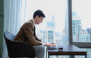 Young businessman sit and relax in the relaxation room by the window overlooking the beautiful city buildings. send message greetings to friends. photo