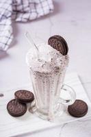 Homemade smoothie with cream and whipped chocolate chip cookies in a glass  vertical view photo