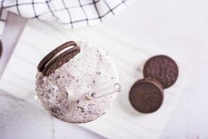 Close up of milkshake of chocolate oreo cookies and ice cream in a glass with a straw top view photo