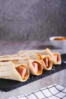 Homemade corn dogs in grilled tortilla with sauce on slate on the table vertical view photo