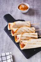 Korean street food corn dog in tortilla grill with sauce on slate on the table vertical view photo