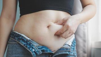 Bauch stecken, schlaff Haut auf ein Fett Bauch, Plastik Chirurgie Konzept auf grau Hintergrund video