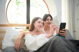 Young couple In the bedroom in the morning, Say hi to pals online using smartphone. photo