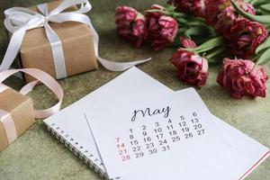 May calendar, gift boxes and tulips bouquet photo