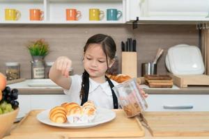 retrato de un pequeño niña en el cocina de un casa teniendo divertido jugando horneando un pan foto