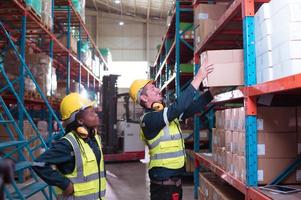 Foreman with employees in warehouse Help each other lift the product boxes to fill them all in the product shelf. After checking the product, it is missing. photo
