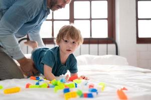 Father with little boy have fun playing with your new toys in the bedroom together. Toys that enhance children's thinking skills. photo