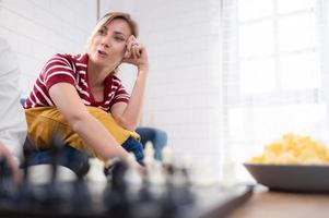 In the living room of the house, an elderly couple sits and relaxes. to begin playing chess together with a chess board with a daughter cheering beside him photo