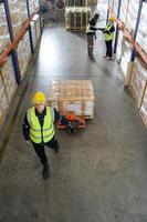 Worker in auto parts warehouse use a handcart to work to bring the box of auto parts into the storage shelf of the warehouse waiting for delivery to the car assembly line photo