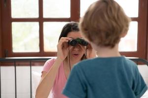 Little boy using small binoculars. A new toy my mom bought me to play with. photo