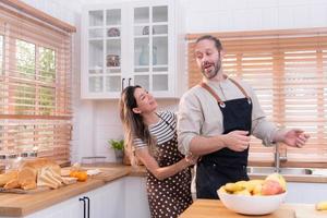 Father and mother in the house's kitchen have a good time making dinner together while awaiting the return of the youngster from school photo