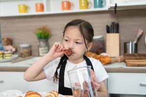 Portrait of a little girl in the kitchen of a house having fun playing baking bread photo