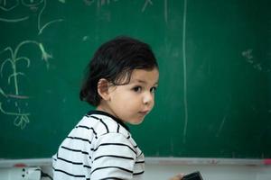 un pequeño chico con un brillante imaginación es claramente visible en el pizarra foto