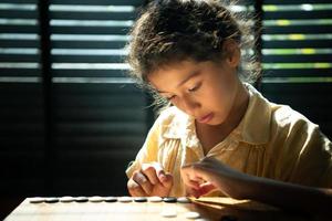 Portrait of a little girl in office room of house with a game of Go being learned to build concentration and intelligence. photo