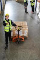 Worker in auto parts warehouse use a handcart to work to bring the box of auto parts into the storage shelf of the warehouse waiting for delivery to the car assembly line photo