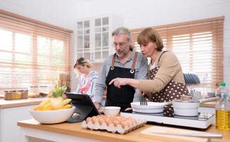 Grandparents with grandchildren and daughter gather in the kitchen to prepare the day's dinner. photo