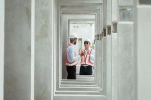 Both of construction engineers verify the constructed precast concrete wall slabs' quality. also to oversee significant construction projects in the construction zone photo