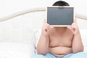 obese fat boy showing blank blackboard photo