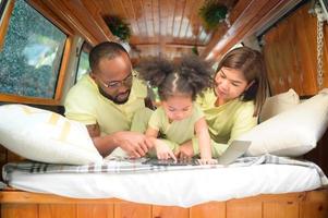 The back of a white classic van, little kids play and learn about the world on their tablet with parents taking care of helping. photo