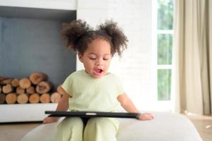 A young bright cute little girl with her trusty tablet that makes her happy and joyful. photo