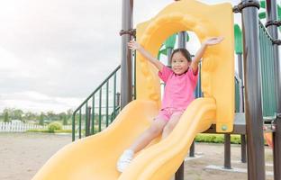 contento asiático niña jugando en niños patio de recreo foto