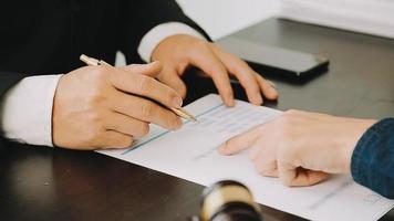 Justice and Law concept. Legal counsel presents to the client a signed contract with gavel and legal law or legal having team meeting at law firm in background video