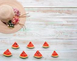 Summer hat and slices of watermelon on weathered wooden background. Flat lay with copy space. photo