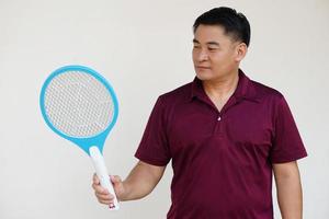 Asian man holds  mosquito electric swatter racket. Concept, Technology electric device to kill mosquitoes, insects, bugs by swatting to flying insects that can cause disease or annoyed feeling. photo